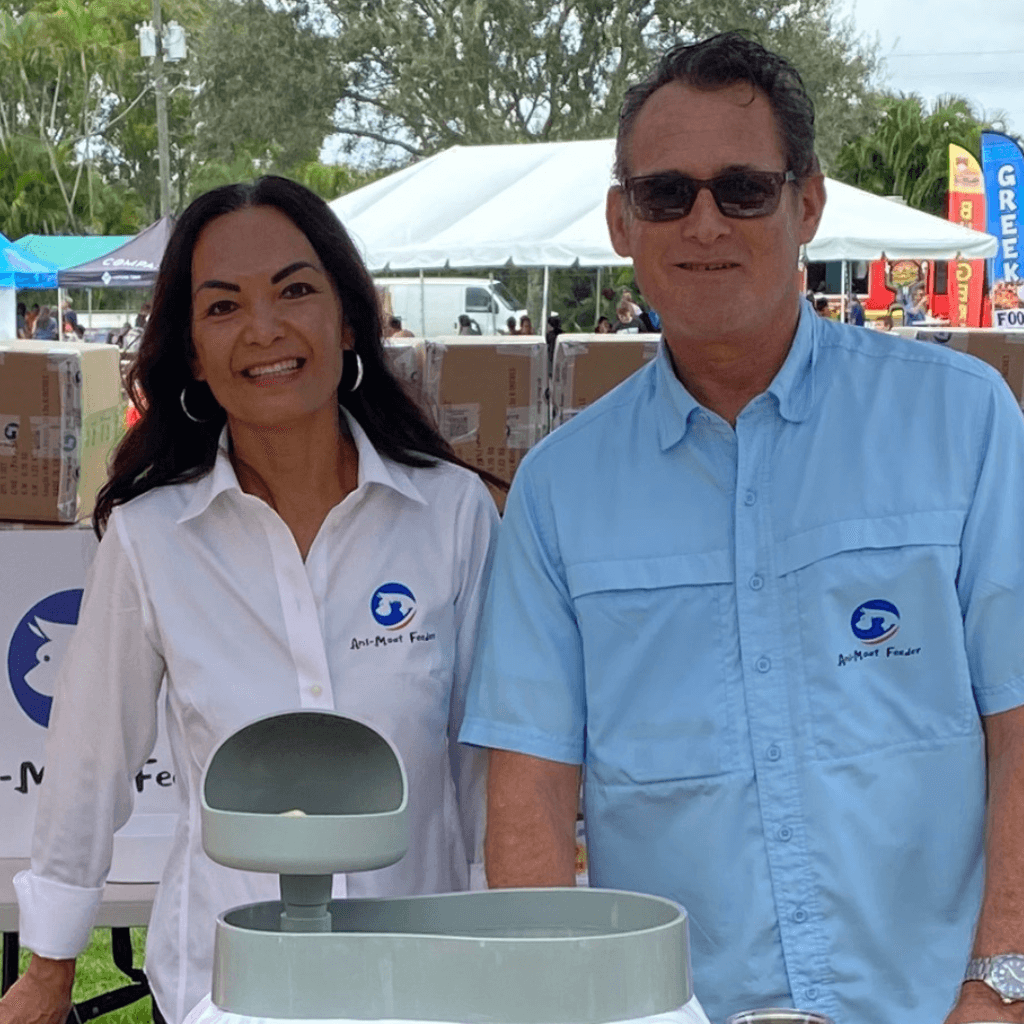 Two people (the founders) wearing branded shirts standing outdoors with tents